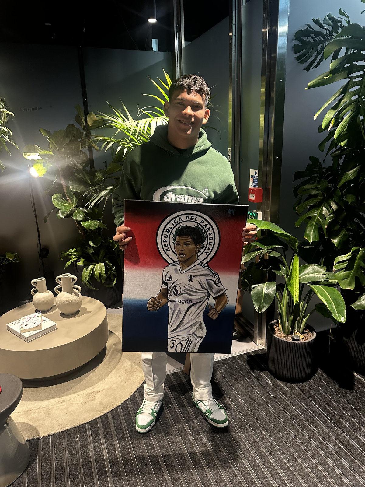 Footballer Diego León smiling and holding his painted portrait
