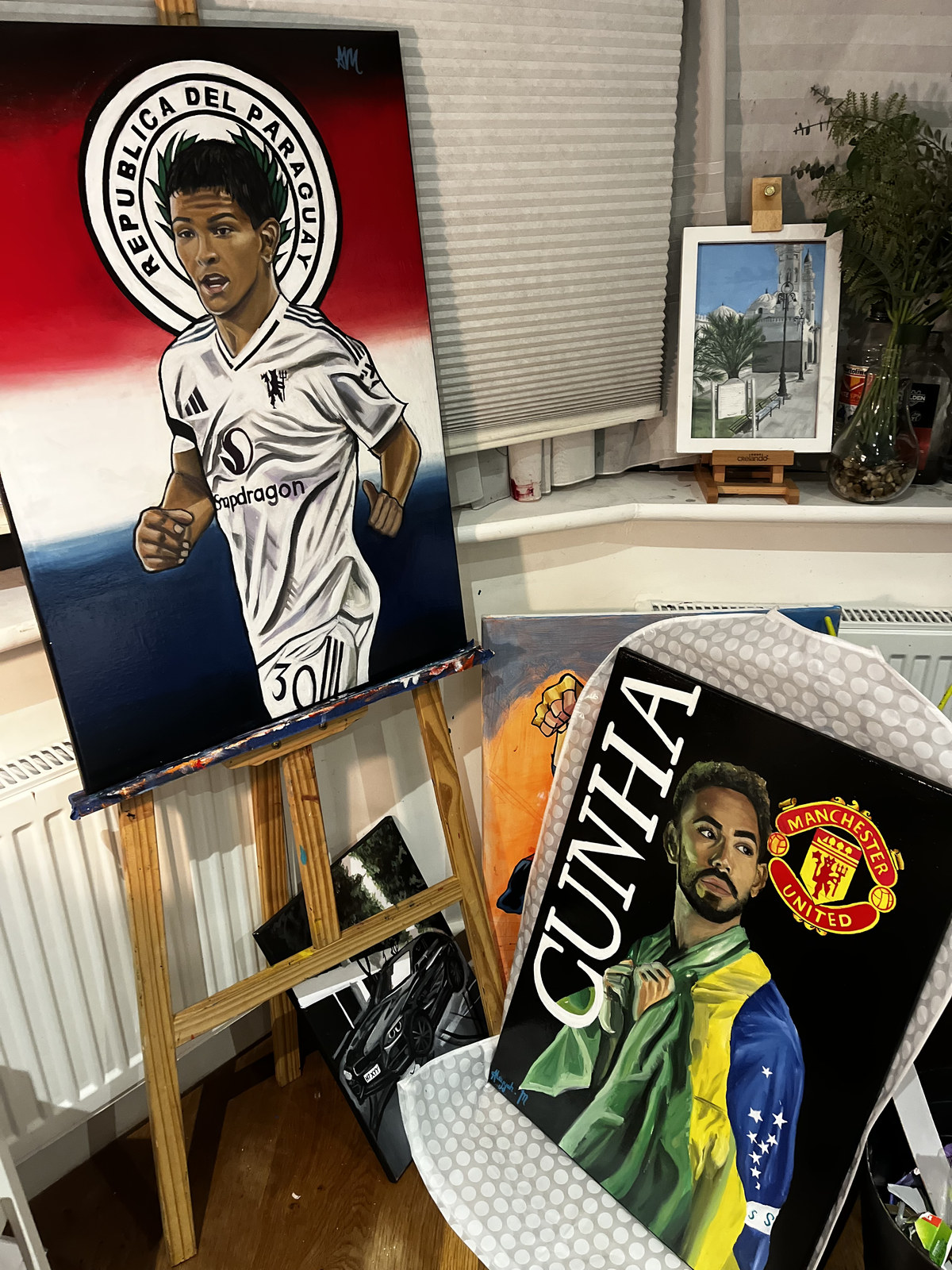 The Diego León portrait on the easel beside the wrapped Matheus Cunha canvas